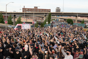 June 4, 2020 Black Lives Matter march in Portland, OR (Matthew Roth) Hundreds of masked people marching across the Morrison Bridge with fists raised, and a pink truck in the background reading "Defund Police"
