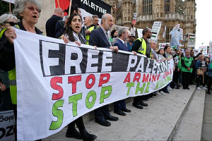 Palestine solidarity protest outside the British Parliament on 5 June 2018. From a London protest: a line of people holding a banner that reads "Free Palestine/ Stop Arming Israel/ Stop the Killing"