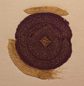 Ap-uh-truh-pay-ik A circular fragment of purple wool is adorned with gold foil and pale silk stitching which displays three overlapping squares