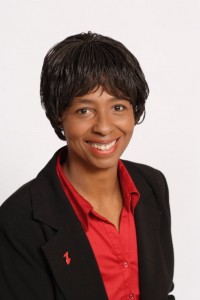 Portrait of Leslie Gregory, a Black woman wearing a red blouse and black jacket.