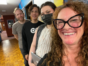 Nathan Vandiver, Ender Black, Arty Wall and Lisa Loving four people lined up in a line, smiling, in a hallway