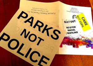 photo by F. Michel handouts from forum: sign "Parks not Police"; sticker "care not cops"