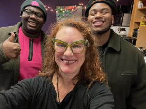 three people smile in the lobby of the community radio station.