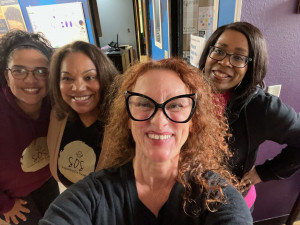 Four women smiling in radio station lobby