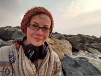 A woman with headphones sitting on rocks